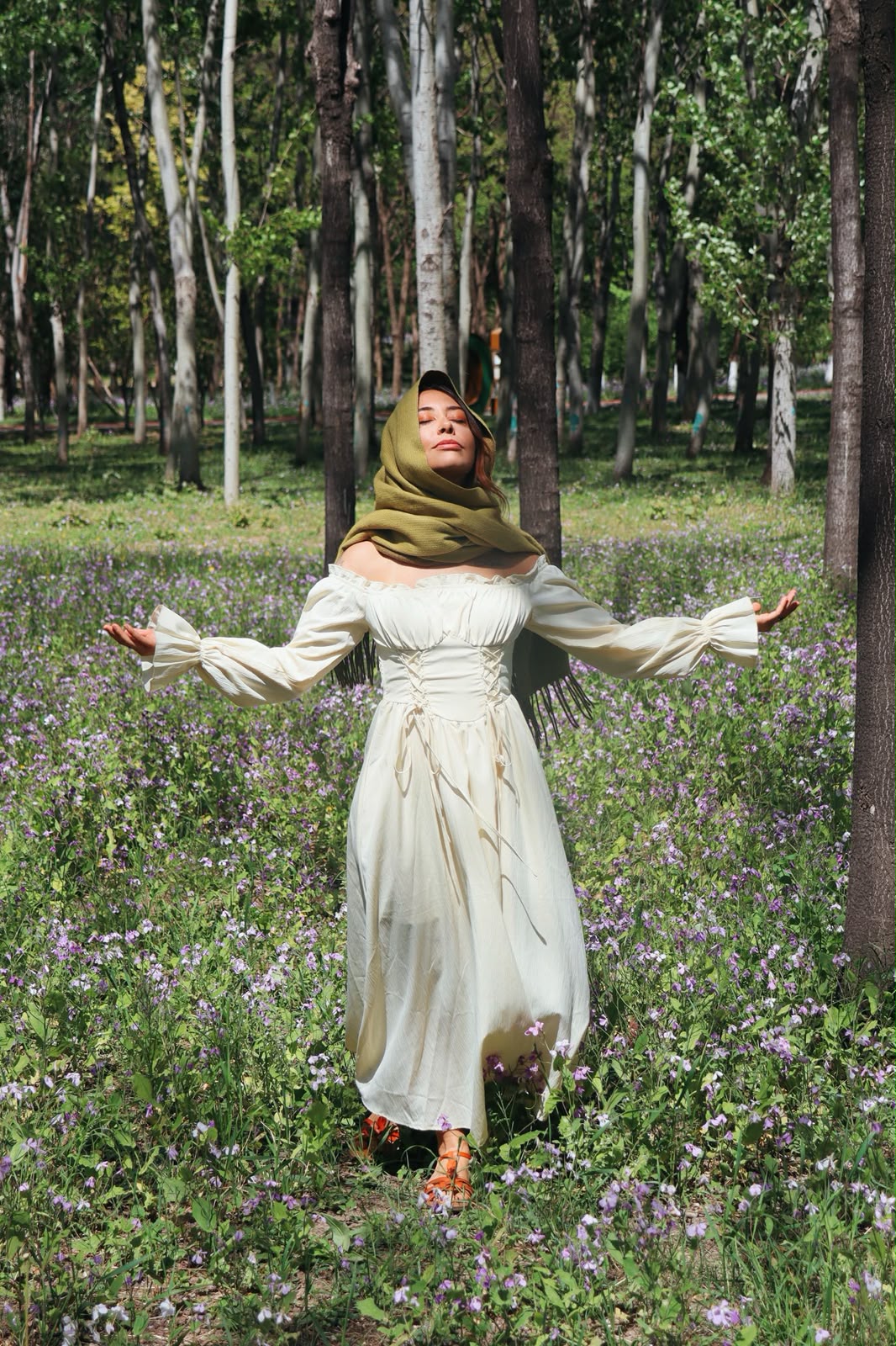 Aline em um campo de flores silvestres na floresta, de braços abertos